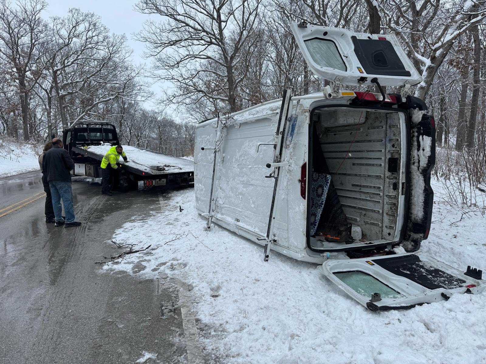 A&N Towing accident recovery team uprighting a rolled-over van on a snowy road near Chicago