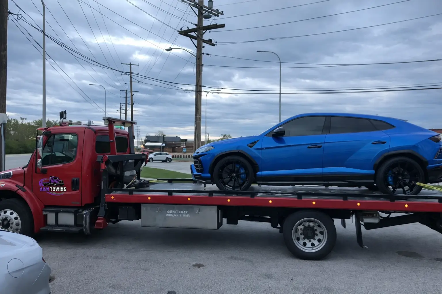 A&N Towing flatbed truck transporting a blue Lamborghini Urus on a Chicago-area road