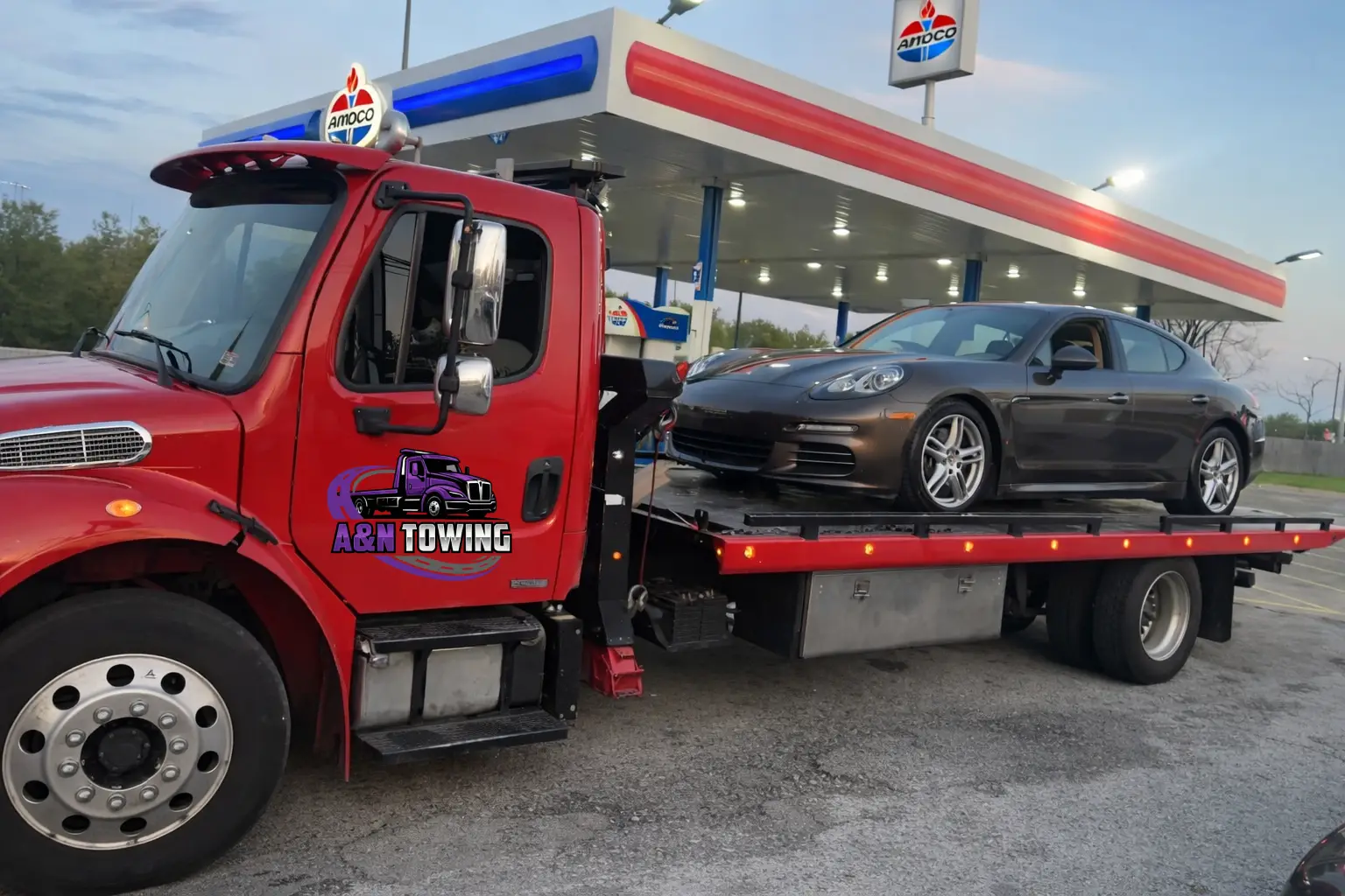 A&N Towing red flatbed truck hauling a Porsche Panamera at an Amoco gas station in Chicagoland